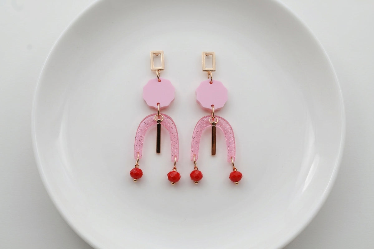 Pink Eva geometric beaded drop earrings arranged on a white plate