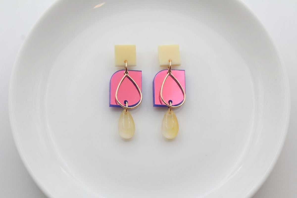 HB Freya small geometric dangle earrings arranged on a white plate