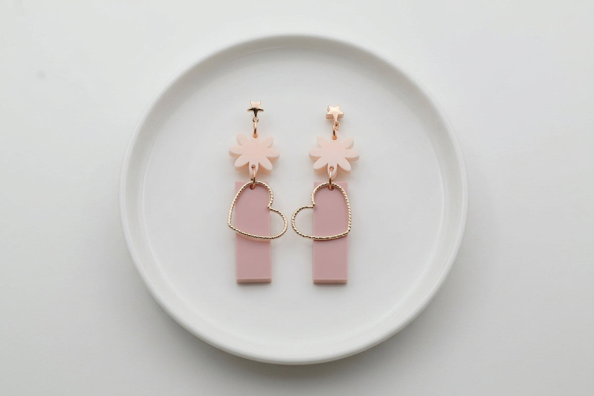 Beige Ines floral heart dangle earrings arranged on a white plate
