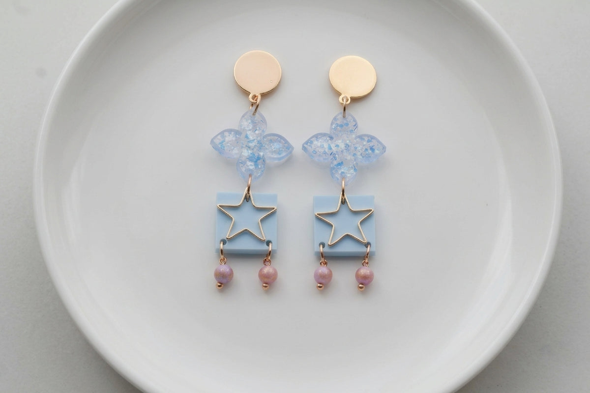 Blue Rose floral star drop earrings arranged on a white plate
