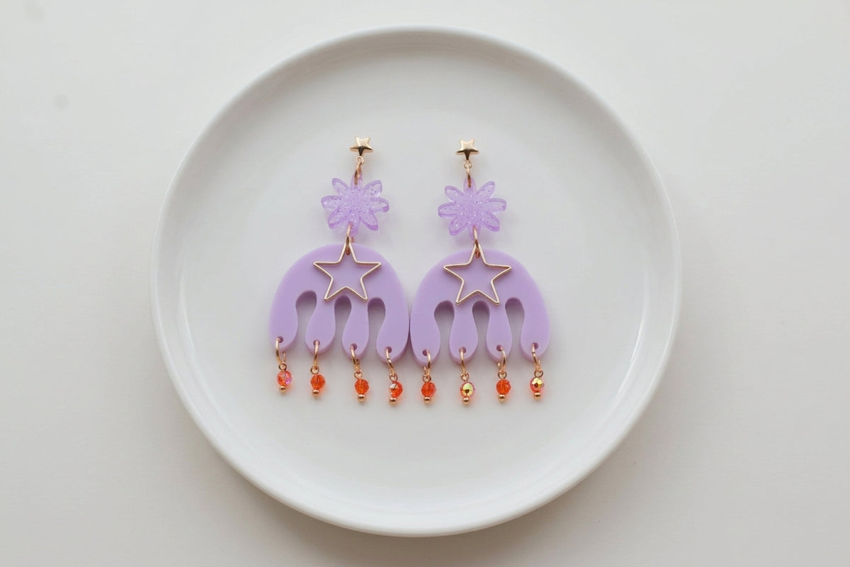 Purple Saar large flower statement earrings arranged on a white plate