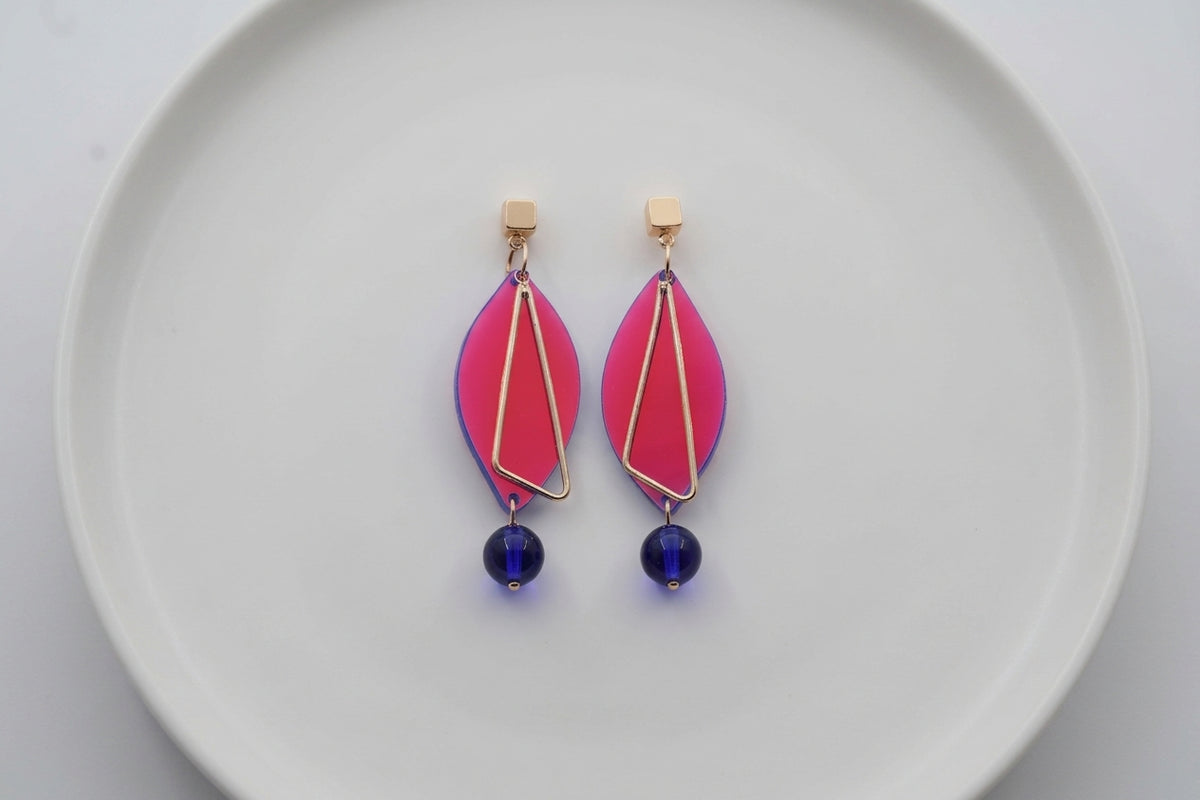 HB Ada geometric acrylic statement earrings arranged on a white plate