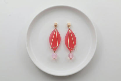 Pink Ada geometric acrylic statement earrings arranged on a white plate