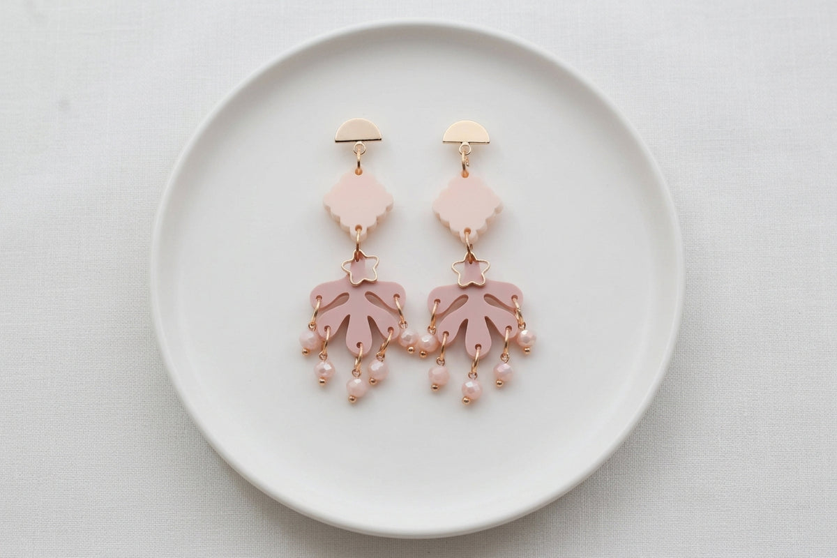 Beige Alba acrylic statement dangle earrings arranged on a white plate