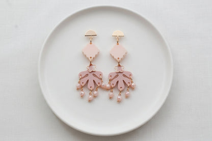 Beige Alba acrylic statement dangle earrings arranged on a white plate