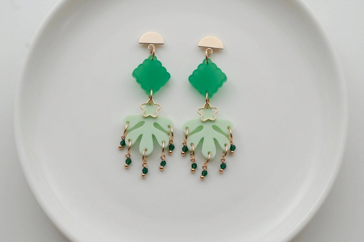 Green Alba acrylic statement dangle earrings arranged on a white plate