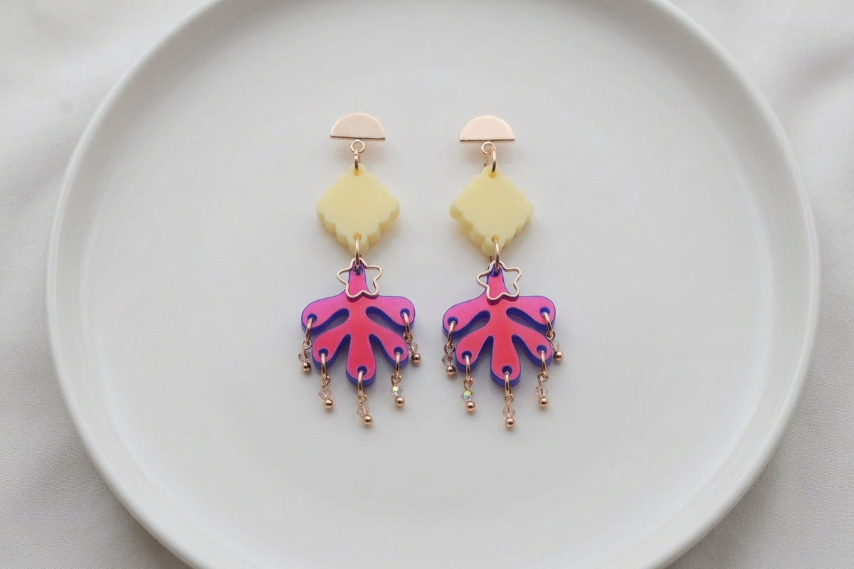 HB Alba acrylic statement dangle earrings arranged on a white plate