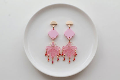 Pink Alba acrylic statement dangle earrings arranged on a white plate