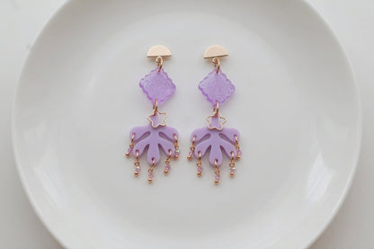 Purple Alba acrylic statement dangle earrings arranged on a white plate