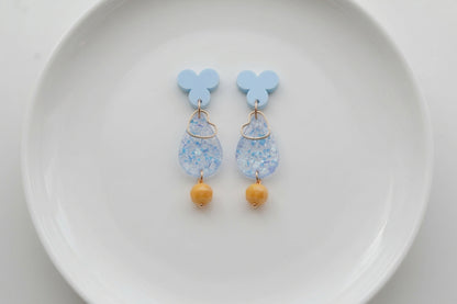 Blue Ana teardrop acrylic dangle earrings arranged on a white plate