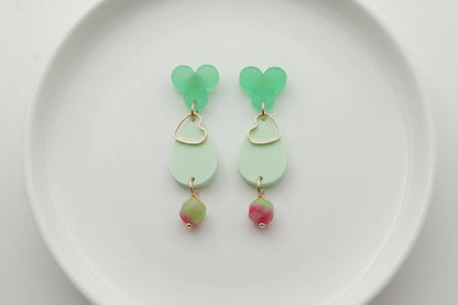 Green Ana teardrop acrylic dangle earrings arranged on a white plate