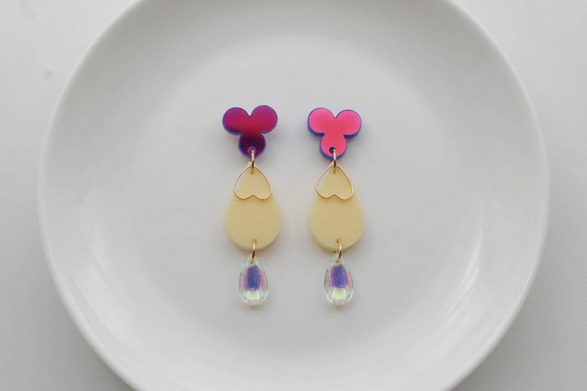 HB Ana teardrop acrylic dangle earrings arranged on a white plate