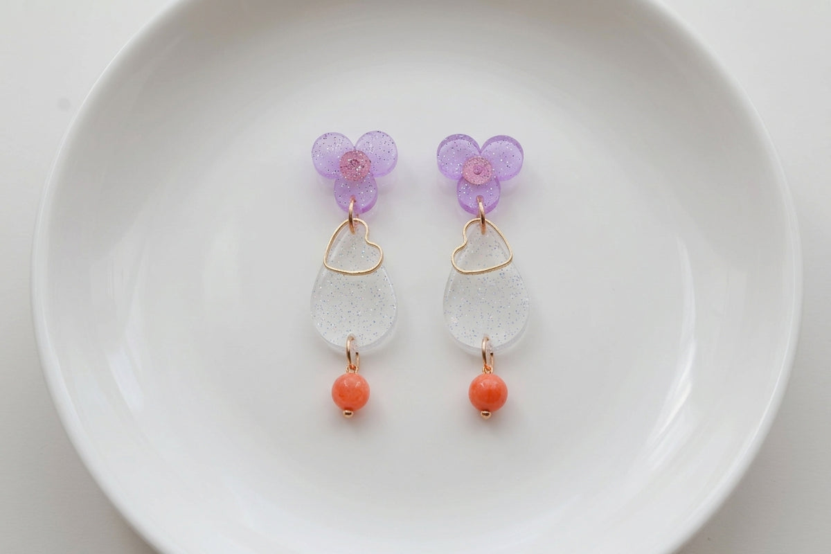 Purple Ana teardrop acrylic dangle earrings arranged on a white plate