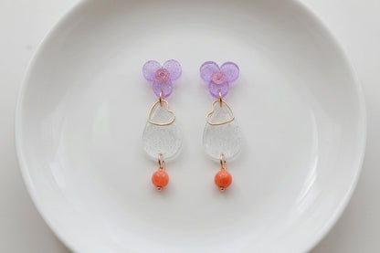 Purple Ana teardrop acrylic dangle earrings arranged on a white plate