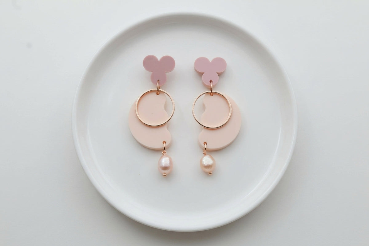 Beige Ayla modern acrylic statement earrings arranged on a white plate
