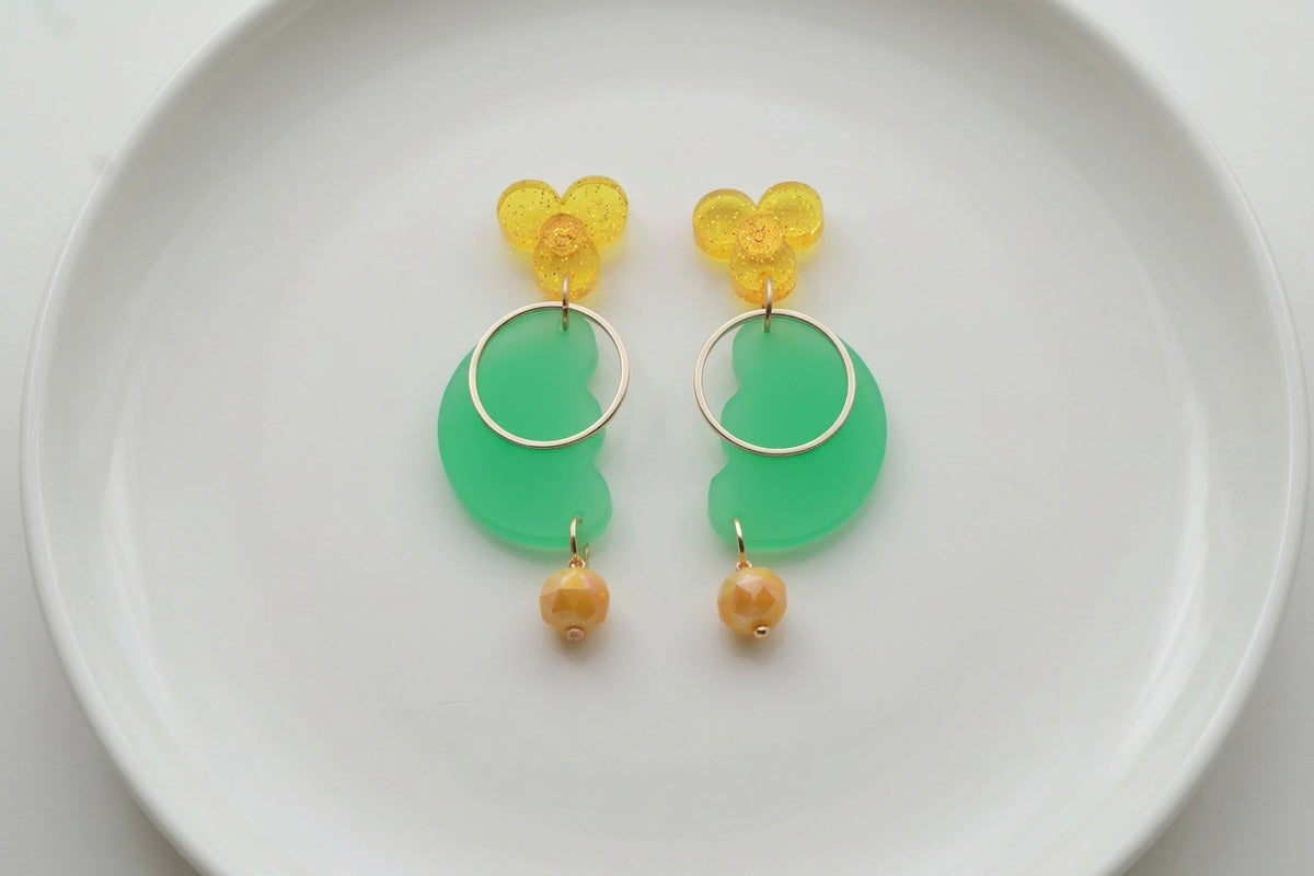 Green Ayla modern acrylic statement earrings arranged on a white plate