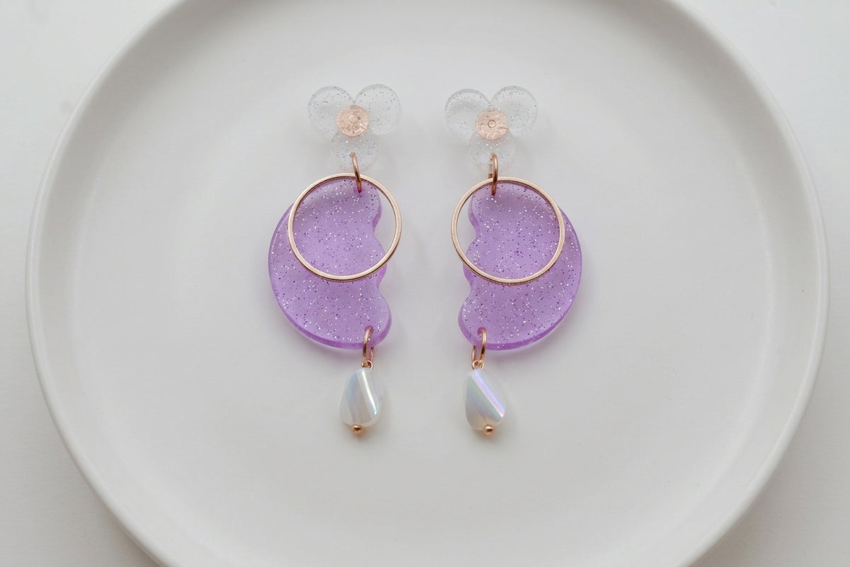 Purple Ayla modern acrylic statement earrings arranged on a white plate