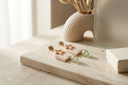 Beige Eira star acrylic drop earrings in a styled product setting