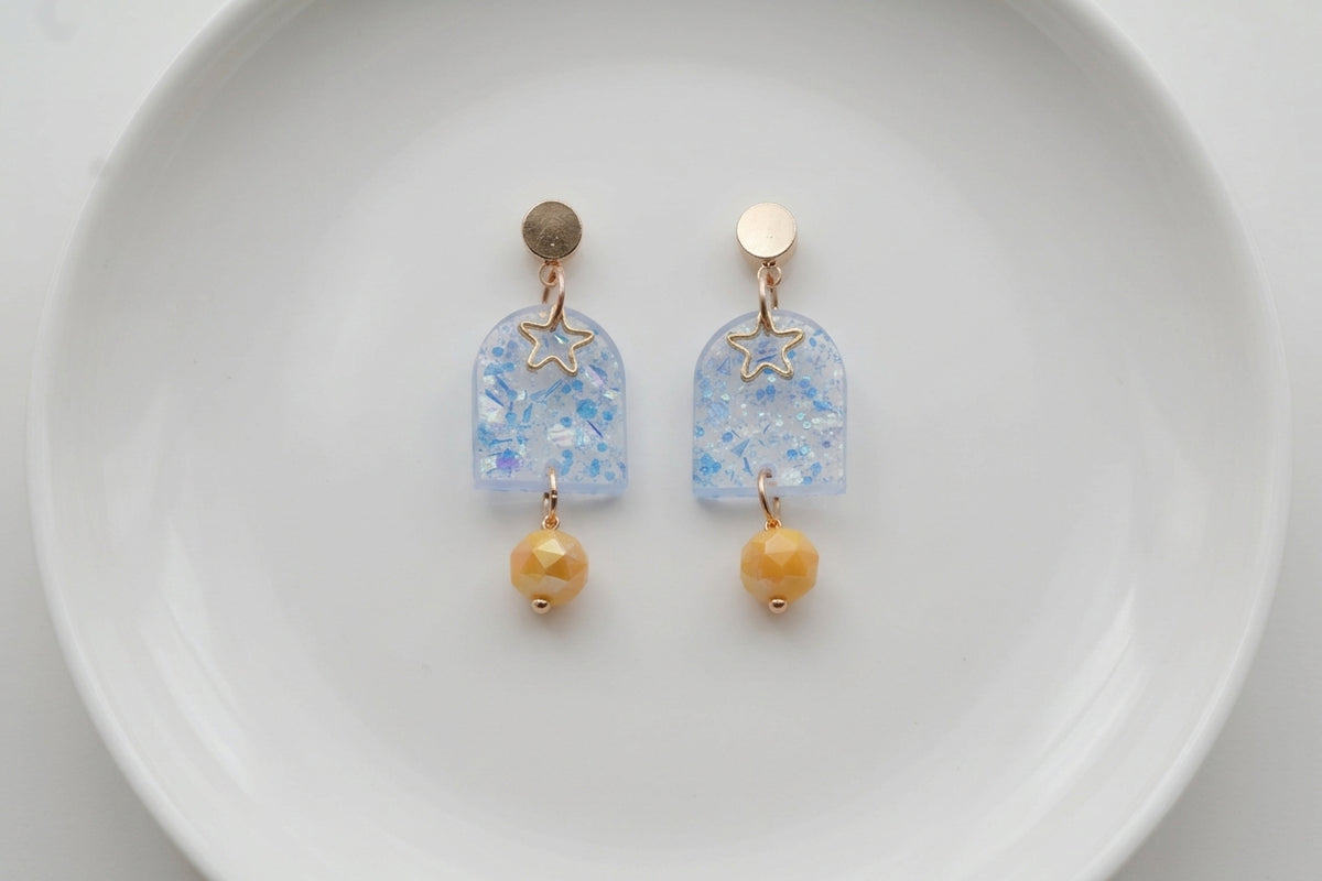 Blue Eira star acrylic drop earrings arranged on a white plate
