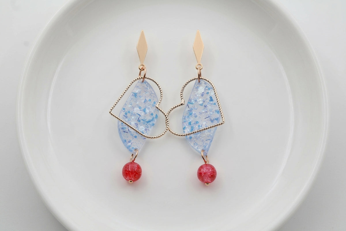 Blue Elise long heart dangle earrings arranged on a white plate