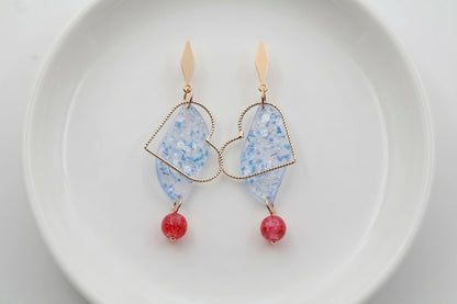 Blue Elise long heart dangle earrings arranged on a white plate