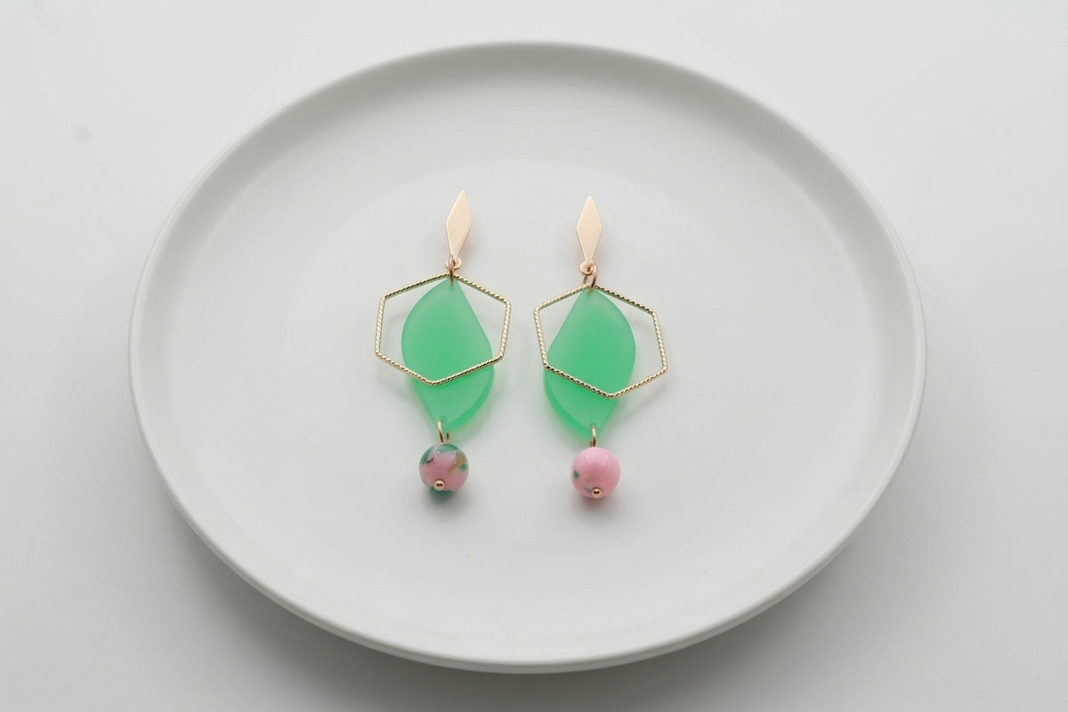 Green Elise long heart dangle earrings arranged on a white plate