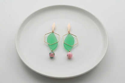 Green Elise long heart dangle earrings arranged on a white plate
