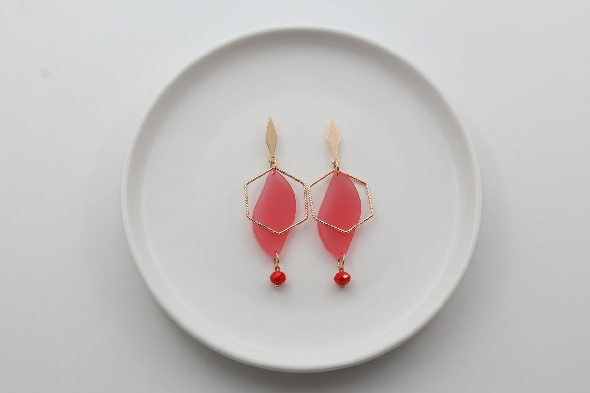 Pink Elise long heart dangle earrings arranged on a white plate