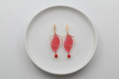 Pink Elise long heart dangle earrings arranged on a white plate