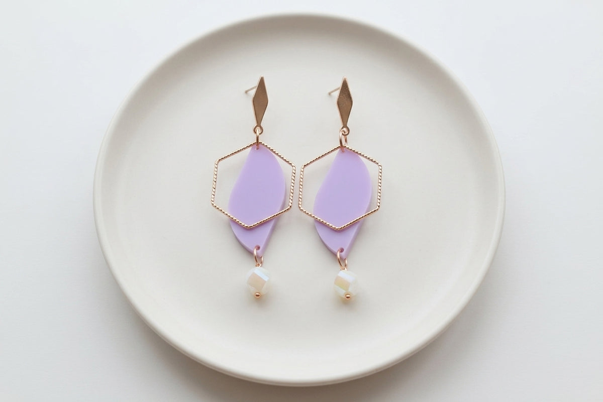Purple Elise long heart dangle earrings arranged on a white plate