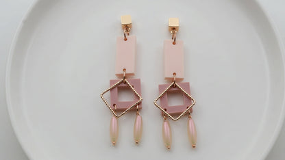 Beige Ella geometric rectangle drop earrings arranged on a white plate