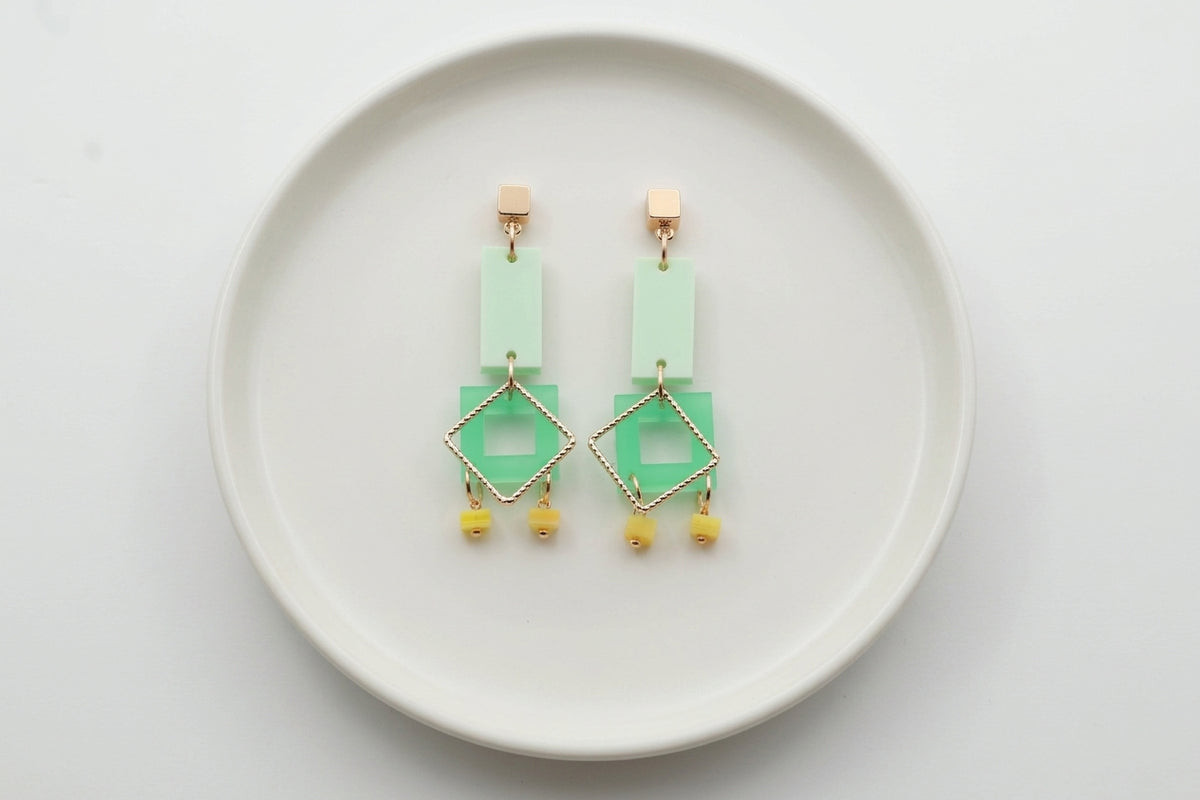 Green Ella geometric rectangle drop earrings arranged on a white plate