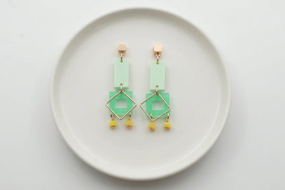 Green Ella geometric rectangle drop earrings arranged on a white plate