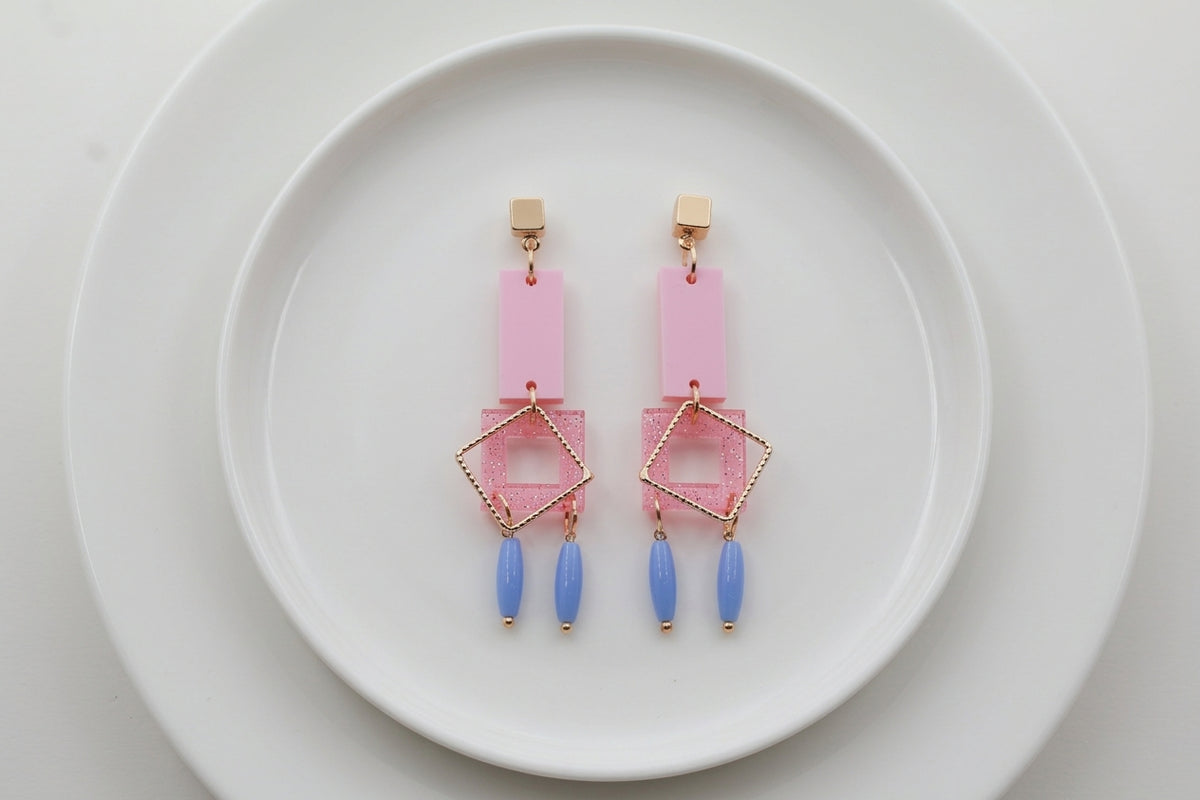 Pink Ella geometric rectangle drop earrings arranged on a white plate