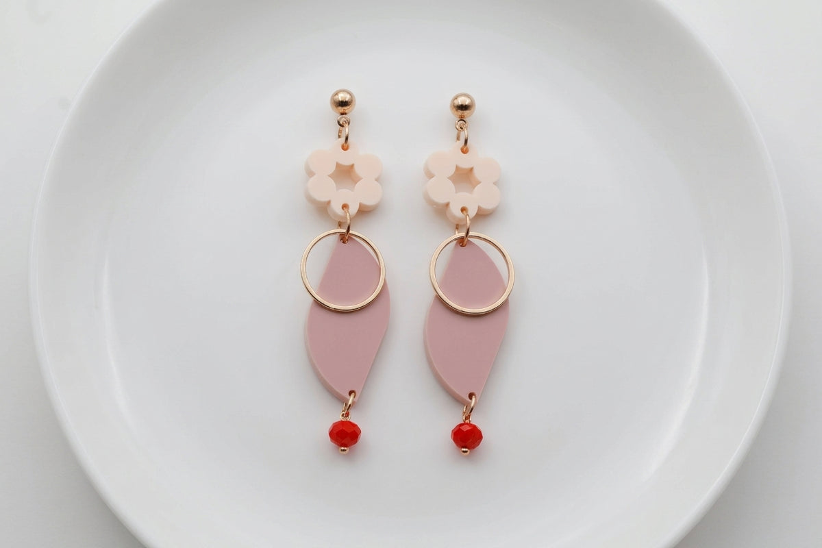 Beige Elsa floral long dangle earrings arranged on a white plate