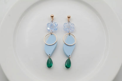 Blue Elsa floral long dangle earrings arranged on a white plate