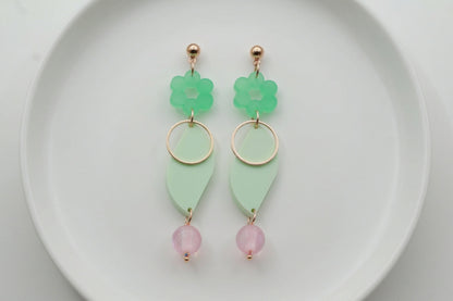 Green Elsa floral long dangle earrings arranged on a white plate