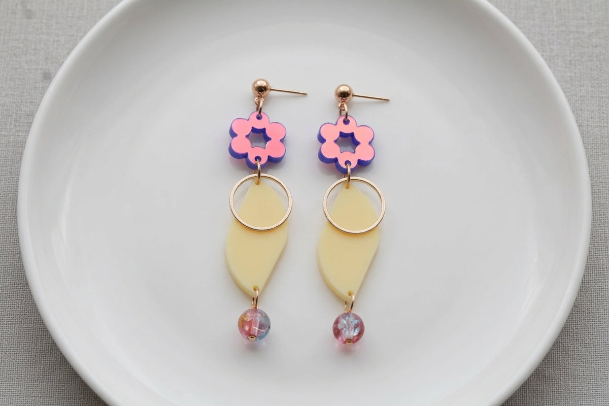 HB Elsa floral long dangle earrings arranged on a white plate