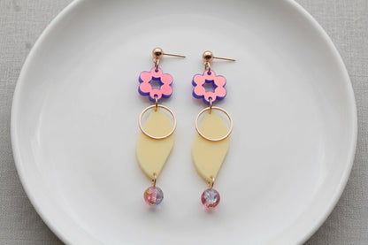 HB Elsa floral long dangle earrings arranged on a white plate