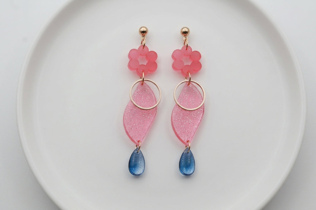 Pink Elsa floral long dangle earrings arranged on a white plate