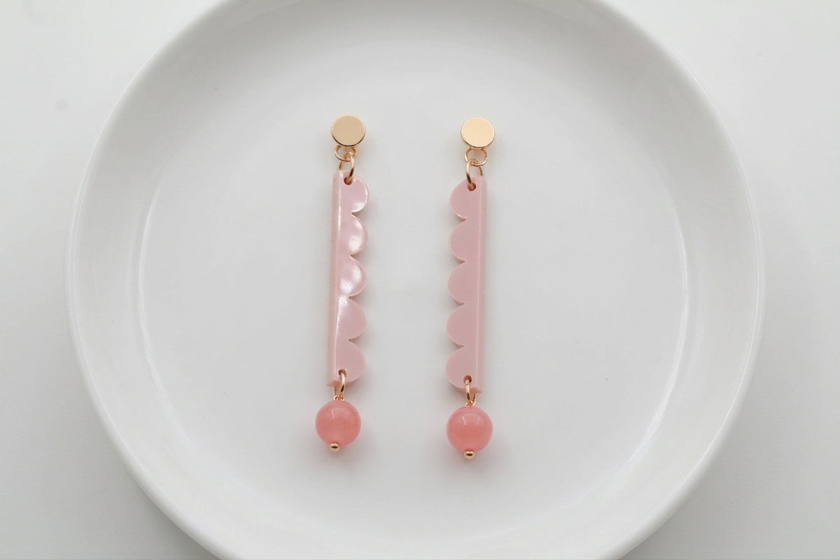 Beige Emma long geometric acrylic earrings arranged on a white plate