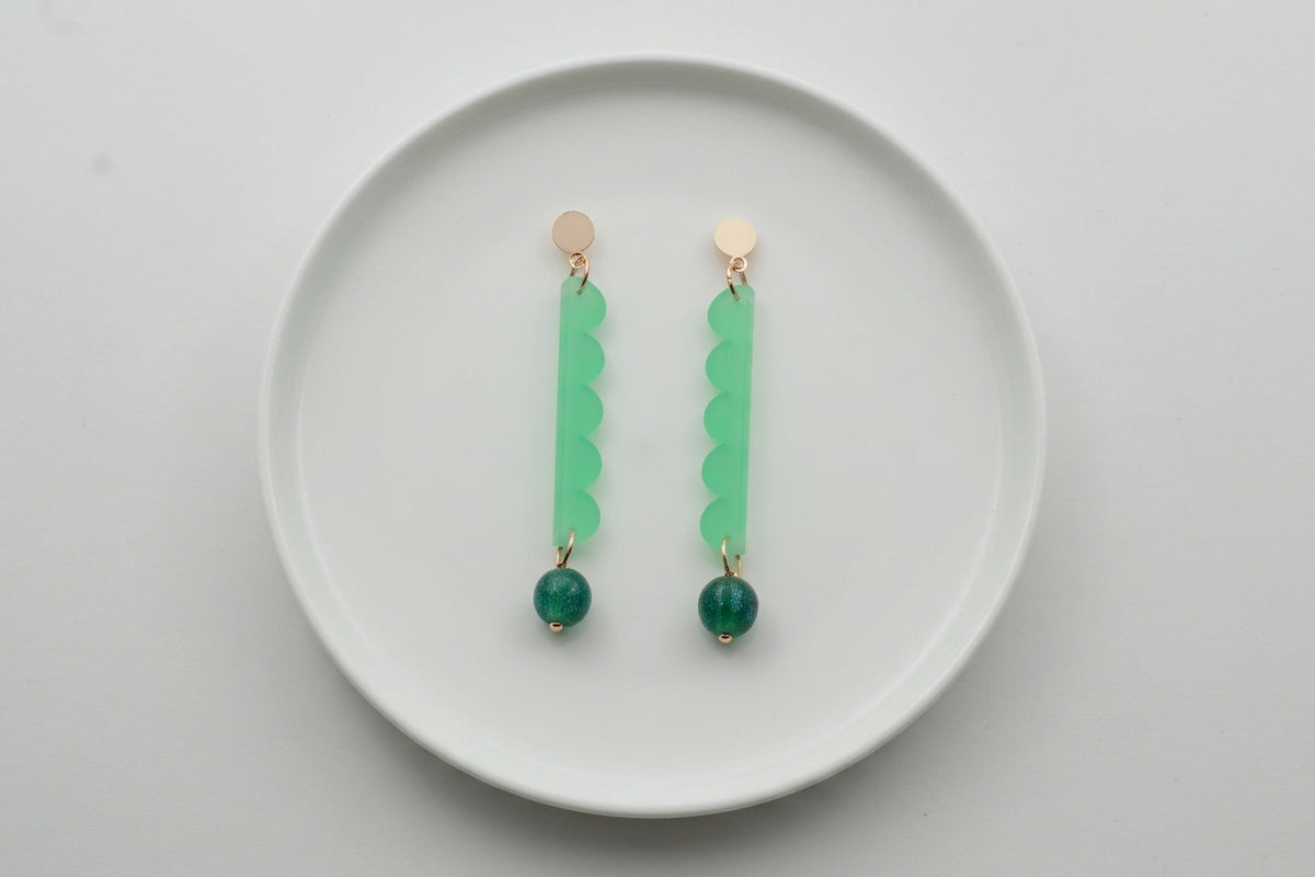 Green Emma long geometric acrylic earrings arranged on a white plate