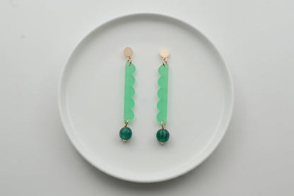 Green Emma long geometric acrylic earrings arranged on a white plate