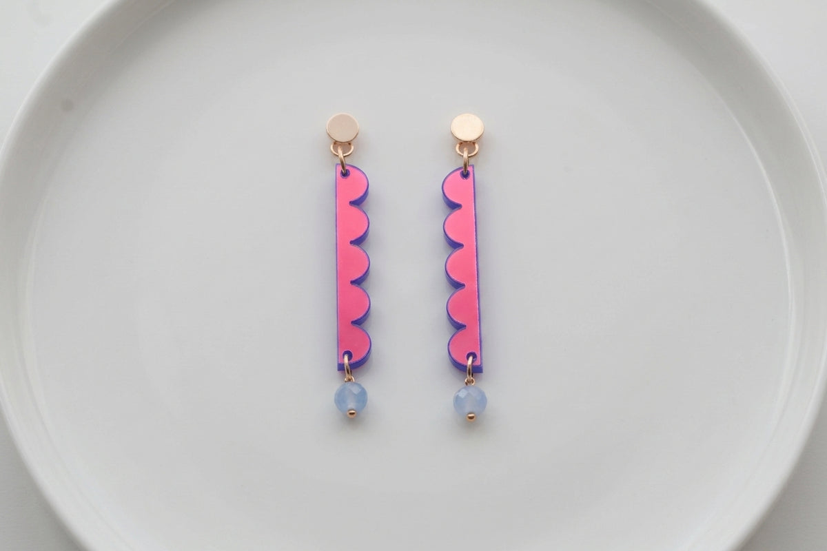 HB Emma long geometric acrylic earrings arranged on a white plate