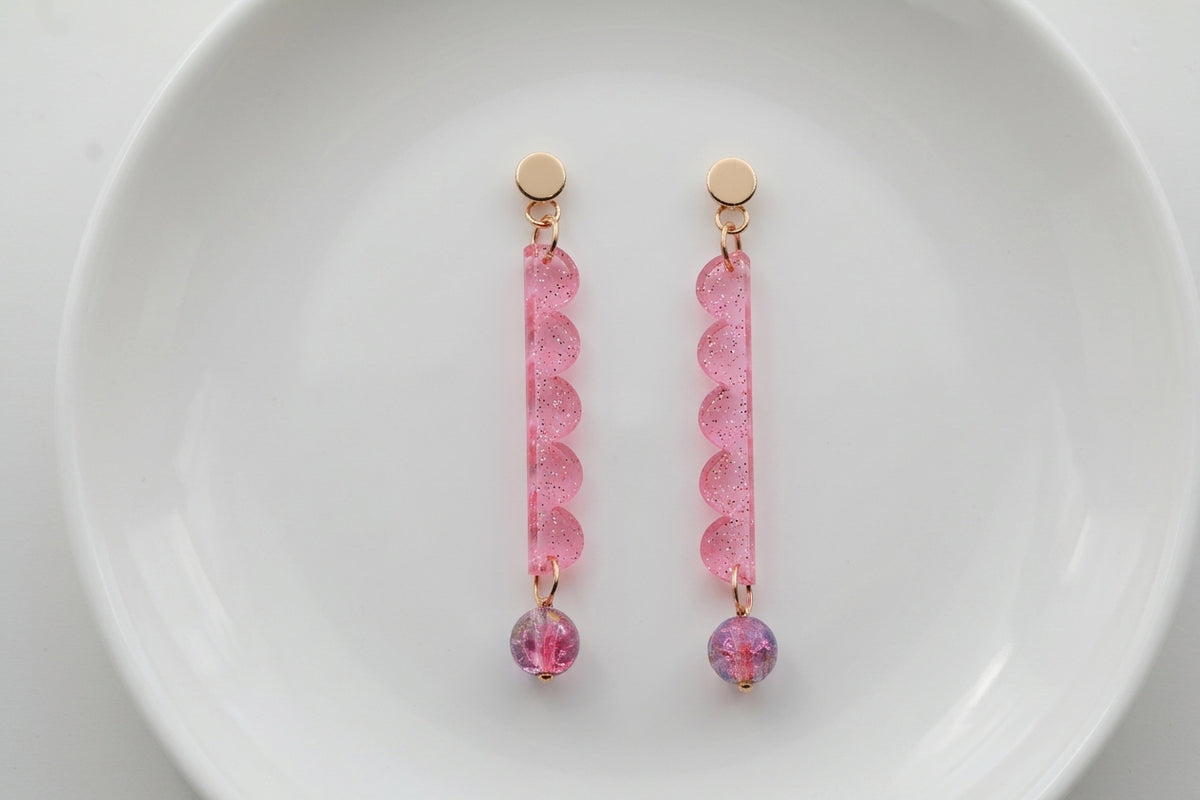 Pink Emma long geometric acrylic earrings arranged on a white plate