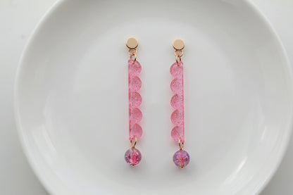 Pink Emma long geometric acrylic earrings arranged on a white plate