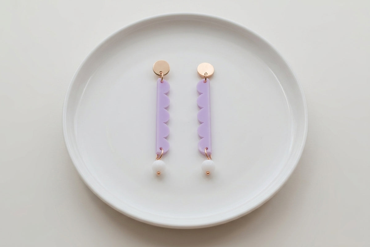 Purple Emma long geometric acrylic earrings arranged on a white plate