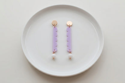 Purple Emma long geometric acrylic earrings arranged on a white plate