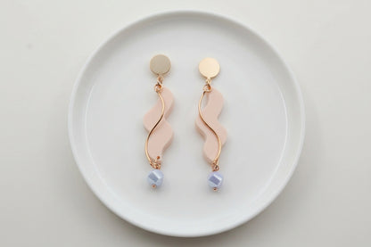 Beige Esme long acrylic statement earrings arranged on a white plate