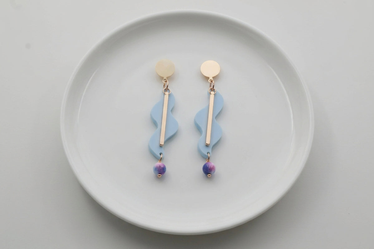 Blue Esme long acrylic statement earrings arranged on a white plate